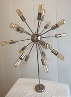 Full view of 17 light chrome chandelier with sputnik style arms and tubular filament bulbs