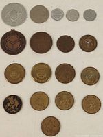 Lot of 18 assorted collectible transit and souvenir tokens arranged on white background showing a variety of sizes, colors, and designs.