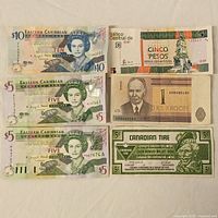 Six bills arranged flat including 3 Eastern Caribbean dollars, Cuban peso, Canadian Tire money, Estonian kroon