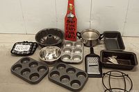 View of all baking and kitchen items: muffin pans, bundt pan, mixing bowl, bread/cake pans, grater, metal stand, decorative tray, and wooden beer opener.