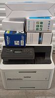 Full front view of Brother HL-L3280CDW printer with toner cartridges stacked on top.