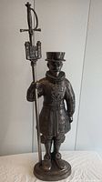 Full view of cast iron Beefeater figurine standing on base holding tall sword