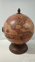 Photo of a decorative globe standing about 16 inches tall with a wooden base, showing the exterior vintage-style map.