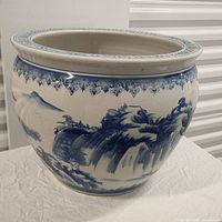 Angled side view showing blue painted landscape decoration and wide rim
