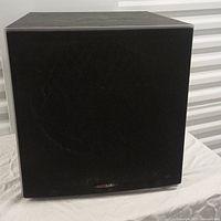 Front view of Polk Audio powered subwoofer with black fabric grille covering the driver.