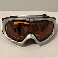 Front view of Uvex ski goggles showing silver frame and orange double lenses with supravision anti-fog label.