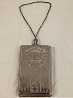 Front view of vintage stainless steel makeup case showing intricate engraving and monogram.