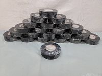 Photo showing all 22 rolls of black electrical tape stacked in a pyramid shape on a white surface.