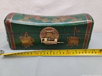 Full view of antique green wooden box with gold painted dragon and fruit motifs; measuring tape showing approximately 30 cm length