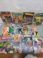 Overview photo of 15 vintage comic books laid out on a surface showing front covers of titles including Uncanny X-Men, Micronauts, Hulk, Batman Outsiders, Superman vs Green Lantern, and others.
