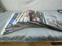 Stack of approximately 18 comic books laid flat on a table, showing a side view of the collection.