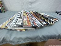 Wide view of a stack of comic books lying flat, showing variety of titles and covers, comics are bagged and boarded.