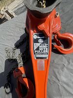 Top view of the orange ratchet lever hoist showing label with '1½ Ton Mini-Mite Puller' and ratchet lever controls.