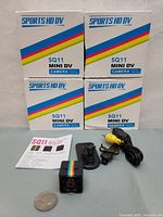 Four boxed Sports HD DV SQ11 Mini DV cameras with accessories shown outside boxes including cables and mounts.