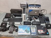 Full overview showing all electronic items including JVC camcorder, network adapter, SSD, smartphone, chargers, and AV switch.