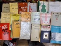 Photo showing many violin music books and sheet music laid out including titles by Haydn, Schumann, Vivaldi, and collections like Stephen Foster Songs.