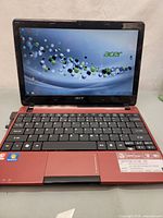 Red Acer Aspire One mini laptop opened to display screen and keyboard with Windows desktop visible