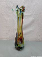 Front view of the tall, flared top multicolor Murano glass vase on a plain background.