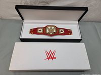 Mini WWE Summerslam 2019 championship belt replica inside white display box featuring WWE logo.
