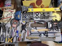 Full overview of all tools and items spread out on a table showing variety of hand tools, measuring tools, and power tool accessories.