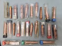 Photo showing 23 torch welding tips of various sizes and shapes, some in plastic protective cases.