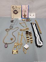 Full lot of vintage jewelry including necklaces, bracelets, earrings, brooch with purple stones on a Celtic card, and a black and white beaded necklace.