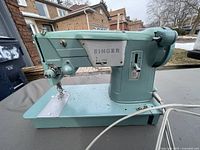 Side view of the vintage Singer 327K sewing machine showing the teal green body, stitch selector, and power cable.