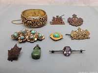 Overview image showing all pins, bracelet, brooches, and pendants arranged on a neutral background.