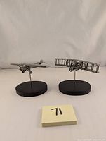 Two pewter model airplanes, the Spirit of St. Louis and Wright Flyer, displayed side by side on black bases against a neutral background.