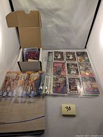 Five sheets of sports cards and two double-sided posters laid out, showing various NBA star rookie cards with a card box.