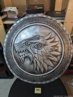 Full view of round shield showing House Stark dire wolf head and decorative border