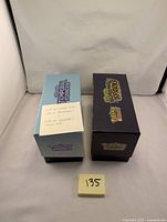 Two closed Pokemon-themed storage boxes labeled 'Temporary Recess' and 'Team Skull Grunt' with a note explaining the contents: over 400 cards and accessories.