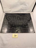 Front cover of the exhibitor's book with black background and outlined STAR WARS text.