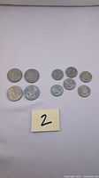 Four USA half dollar coins and six USA quarter dollar coins laid on a white cloth with a lot number card.