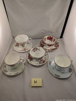 Front view of five vintage floral bone china teacups and saucers with gold trim arranged together