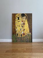 Full front view of the plaque showing Gustav Klimt's "The Kiss" upright against a wall on hardwood floor.