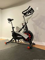 Full left-side view of bike on mat showing frame, saddle, handlebars and flywheel