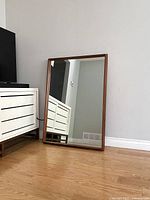 Full view of mirror leaning against living room wall beside media console