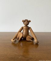Front view of the mid-century teak monkey sitting upright showing its design and wood texture.