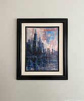 Framed cityscape artwork showing skyline and bridge with reflective water beneath.