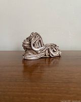 Side view of vintage dog figurine showing detailed twisted metal work and elongated form.