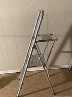 Side view of the aluminum 2-step ladder showing the steps and support structure.