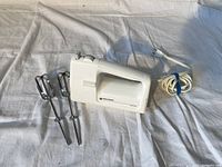 White Black & Decker hand mixer body with two chrome metal beater attachments and coiled white power cord