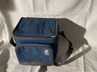 Blue soft cooler bag closed showing front pocket and shoulder strap