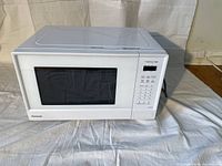 Front view of Panasonic Genius white microwave with closed door, control panel on right side.