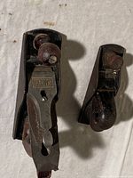 Photo of two handheld construction planers, one labeled 'SABERSON', showing wooden handles, knobs, and rusted metal bases.