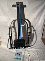 Front view of the West Bend 5100 rowing machine, showing padded seat, hydraulic resistance arms, and vertical frame with blue stripe.