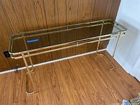 Full side angled view showing the smoked glass tabletop and gold metal frame with curved legs.