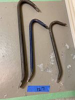 Image showing three crow bars of different sizes and colors laid on a floor surface, with a blue tape label '127' next to them.
