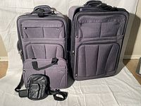 Photo showing large and medium suitcases along with the smaller carry-on and tote bag all in gray fabric with black handles and accents.